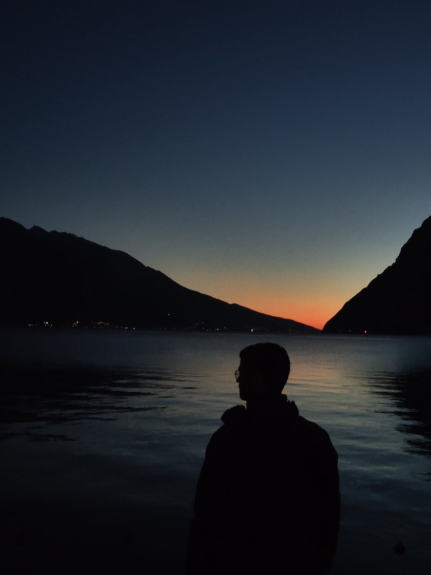 Krishnam Soni in silhouette, watching the sunset over Lake Garda between two mountains